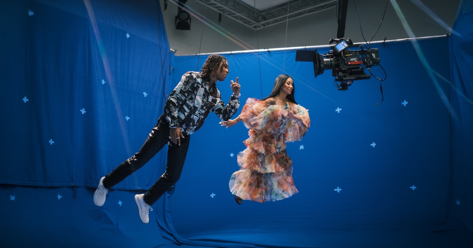 Two performers suspended against a blue screen under a camera rig