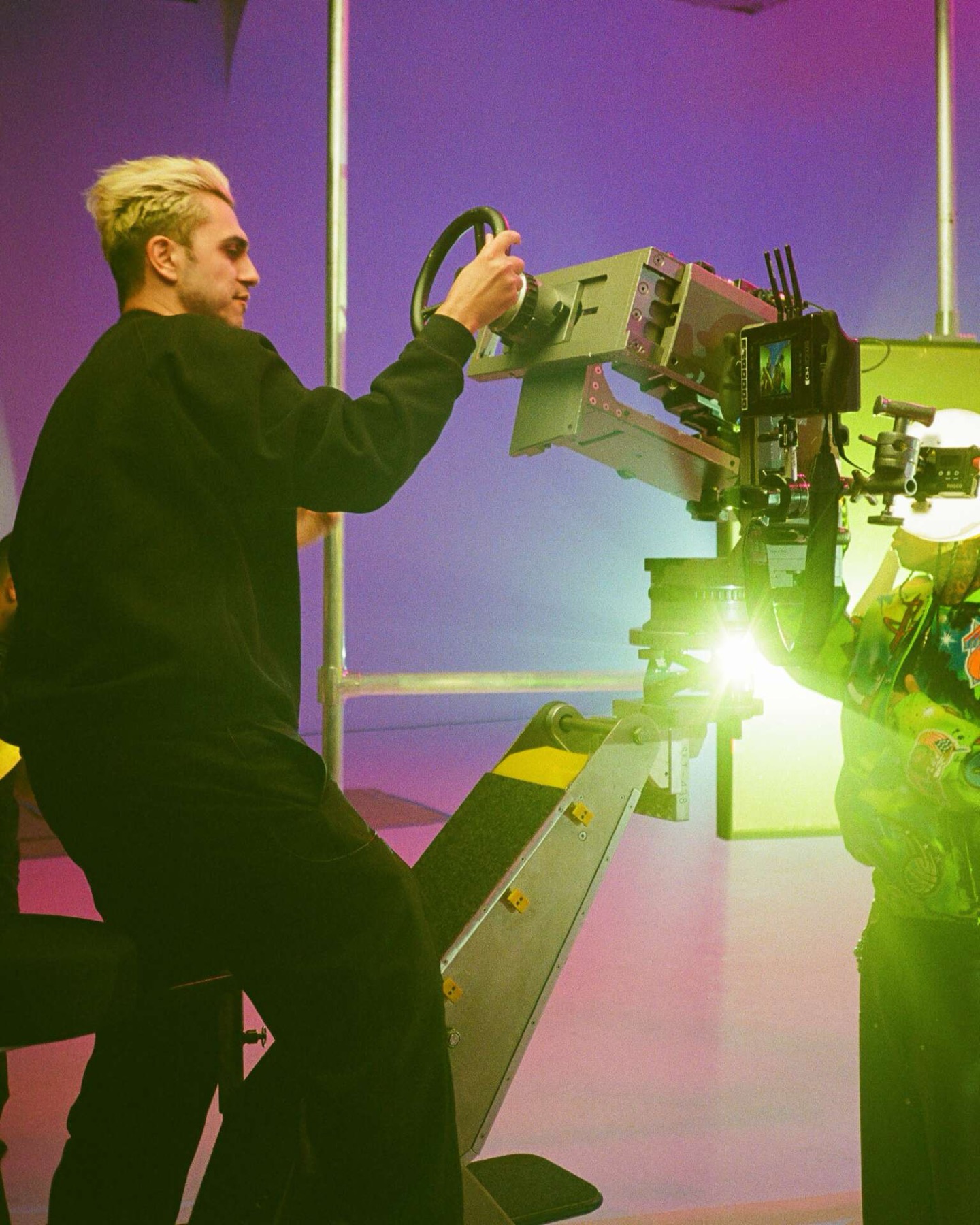 Arrad operating a camera crane against a purple backdrop