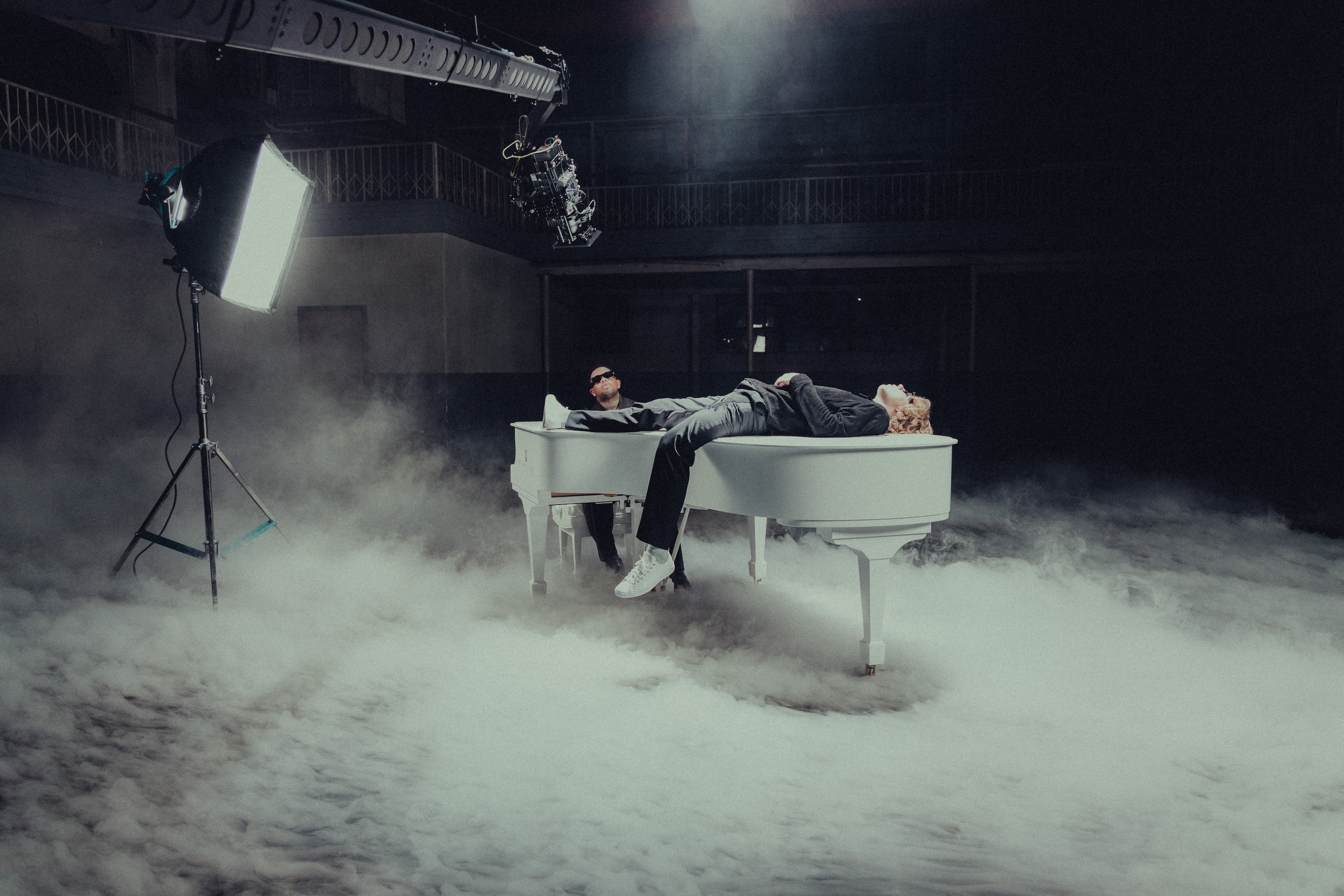 A white grand piano in rolling fog under a lighting rig