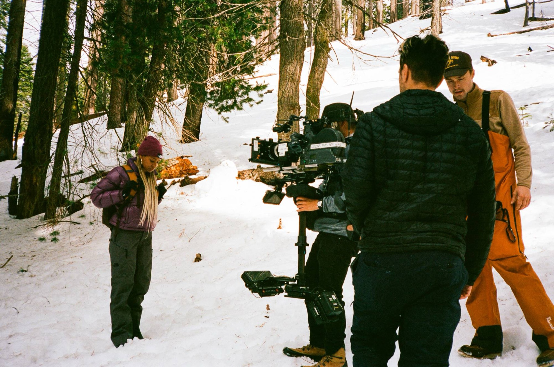 Steadicam operator and crew filming in a snowy forest